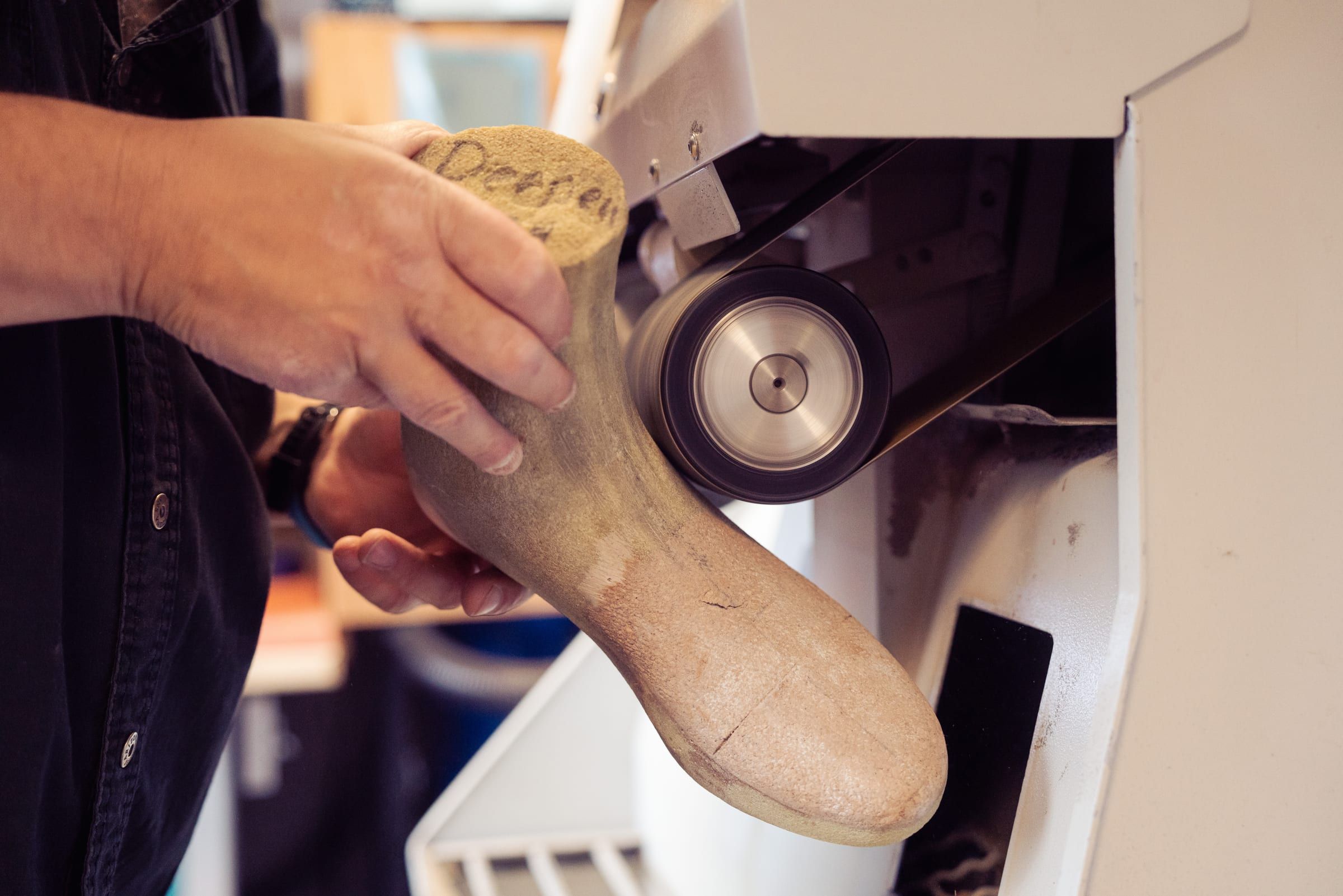Ein Schuhleisten wird in der Werkstatt von Hand geschliffen
